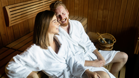 Man and woman wearing robes inside a sauna