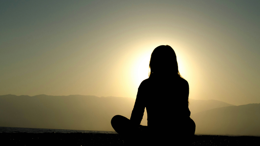 Silhouette Of A Woman Sitting Cross-Legged, Basking In The Sunset